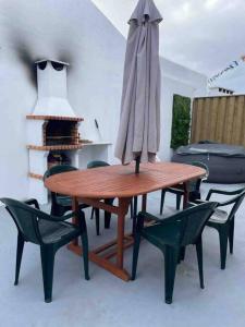 un tavolo in legno con sedie e ombrellone di Alvarenga House a Maia