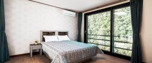 - une chambre avec un lit et une grande fenêtre dans l'établissement Yoninsan Spring Resort, à Gapyeong