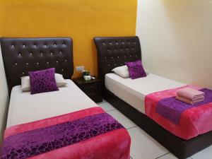 two beds sitting next to each other in a room at Mimilala Hotel @ i-City, Shah Alam in Shah Alam