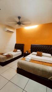 two beds in a room with orange walls at Mimilala Hotel @ i-City, Shah Alam in Shah Alam