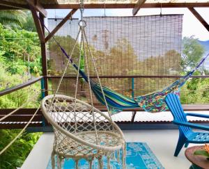 a hammock on a porch with two chairs at L'Auberge de Tahiti Iti - Beach hostel in Afaahiti