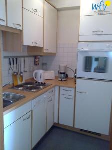 a kitchen with white cabinets and a white refrigerator at Ferienhaus Seeblick Ferienwohnung 65 in Borkum