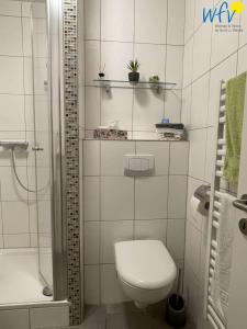 a white bathroom with a toilet and a shower at Ferienhaus Seeblick Ferienwohnung 65 in Borkum