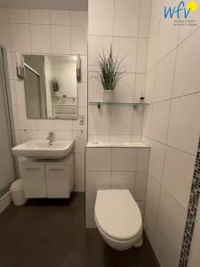 ボルクムにあるFerienhaus Seeblick Ferienwohnung 53のトイレと洗面台を備えた白いバスルーム +14枚の写真