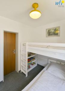 1 dormitorio con litera blanca y puerta en Dünenschlösschen Ferienwohnung 10, en Wangerooge