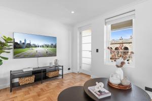 een woonkamer met een tv aan een witte muur bij Elegant & Stylish Home by the Botanical Gardens in Melbourne