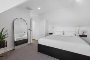 een witte slaapkamer met een groot bed en een spiegel bij Elegant & Stylish Home by the Botanical Gardens in Melbourne