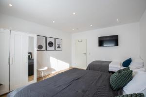a white bedroom with a bed and a tv at CARICASA: Bielefeld Mitte in Bielefeld