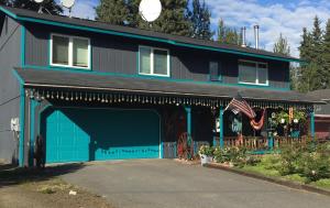 une maison avec un garage bleu et drapeau américain dans l'établissement Northern Knights, à Fairbanks