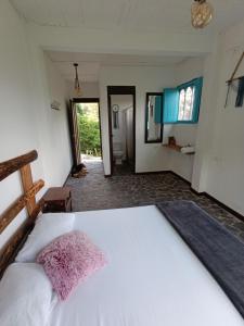 1 dormitorio con 1 cama blanca grande con almohada rosa en Hostal Payaca, en Bituima