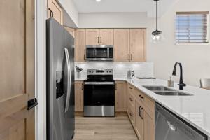 a kitchen with wooden cabinets and a black refrigerator at Powder Heights #21 townhouse in Sun Peaks