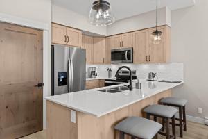 a kitchen with a stainless steel refrigerator and stools at Powder Heights #21 townhouse in Sun Peaks