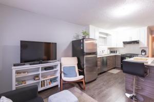 a kitchen with a stainless steel refrigerator and a tv at Suite Sunrise in Vancouver