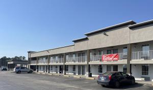 a large building with cars parked in a parking lot at Red Roof Inn Dunn in Dunn