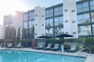 a pool with chairs and umbrellas in front of a building at Four Points by Sheraton San Rafael Marin County in San Rafael
