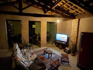 a living room with a couch and a flat screen tv at Casas Goiás - Suítes Beira Rio - Centro Histórico in Goiás