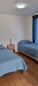 Duas camas num quarto com edredão azul em Refugio Pucalan Lodge em Puchuncaví
