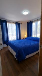 um quarto com uma cama azul com cortinas azuis em Refugio Pucalan Lodge em Puchuncaví