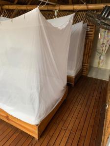 a tent on a wooden deck with white sheets at Cabaña Beach Palomino in Palomino