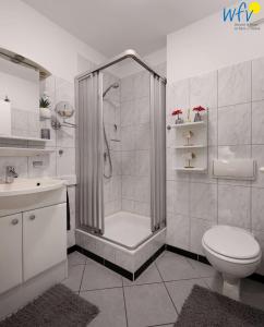 a white bathroom with a shower and a toilet at Haus Bahnhofstraße 11a Ferienwohnung 7 in Wangerooge +16 photos