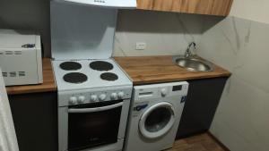a small kitchen with a stove and a washing machine at трёхкомнатная после ремонта с удобным расположением in Karagandy