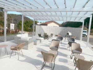 a patio with chairs and tables and a white pergola at Sloth Glamping in Izumi