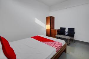 1 dormitorio con 1 cama, escritorio y 2 sillas en Super OYO Flagship The Mahalaxmi Inn, en Dibrugarh