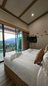 a bedroom with a large bed with a large window at Soidao Good View Resort in Ban Thap Sai