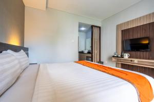 a bedroom with a large white bed with a flat screen tv at Casa Dasa Legian in Seminyak