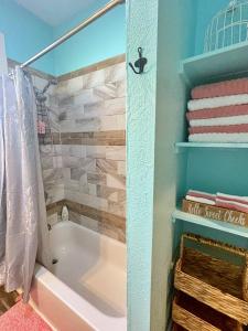 y baño con bañera, toallas y ducha. en The Poolside Bungalow en Galveston