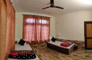 a living room with two beds and a ceiling fan at One More Night hostel and community living in McLeod Ganj