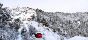 a mountain covered in snow with houses on it at THE GRAND RESORT DHANOLTI in Dhanaulti