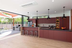 Una cocina abierta con gabinetes rojos y un comedor. en Brand-new 8BR Private Pool Villa Mystic Garden, en Rawai Beach