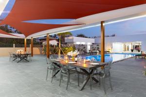 Un patio al aire libre con mesas y sillas y una piscina. en Brand-new 8BR Private Pool Villa Mystic Garden, en Rawai Beach