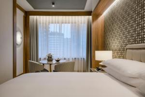 a bedroom with a bed and a table and a window at AC Hotel Cuzco by Marriott in Madrid