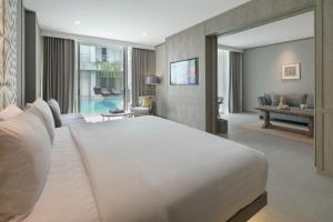 a bedroom with a large white bed and a living room at Kanvaz Village Resort Seminyak in Seminyak