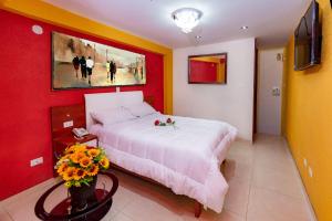ein Schlafzimmer mit einem weißen Bett und einer roten Wand in der Unterkunft HOSTAL TAU TACNA in Tacna