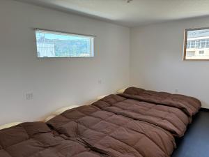 Una cama en una habitación blanca con ventana. en Guesthouse Fujinokura Kawaguchiko Ekimaeten, en Fujikawaguchiko