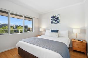 a white bedroom with a large bed and a window at Applecross Riverside Apt in Perth