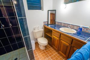 y baño con aseo, lavabo y ducha. en Hotel Chillies and Native Sons Diving, en West End