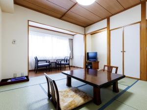 Una sala de estar con una mesa y sillas y un televisor. en Tabist Hotel Nemuro Kaiyoutei, en Nemuro
