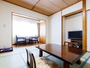 Tabist Hotel Nemuro Kaiyoutei في نيمورو: غرفة طعام مع طاولة وتلفزيون