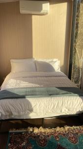 Una cama con sábanas blancas y almohadas en un dormitorio en Longford Tiny Houses, en Longford