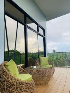 two chairs and a table on a balcony with windows at Jinjer Resort in Cavinti