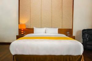 1 dormitorio con 1 cama grande con manta blanca y amarilla en Louis Kienne Bandungan, en Srondolwetan