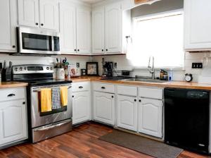 a kitchen with white cabinets and stainless steel appliances at Roman’s Retreat in Fayetteville