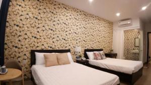 1 dormitorio con 2 camas y una pared cubierta de flores en Khách Sạn Nhơn Lý LYS HOTEL, en Quy Nhon