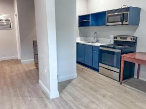 eine Küche mit blauen Schränken, einer Spüle und einer Mikrowelle in der Unterkunft El Cajon Inn & Suites in El Cajon