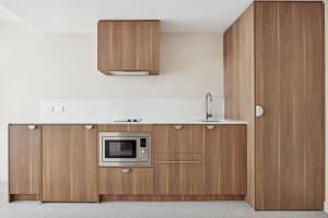a kitchen with wooden cabinets and a microwave at Abode Phillip in Canberra