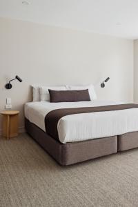 a bedroom with a large bed with two lamps on it at Abode Phillip in Canberra